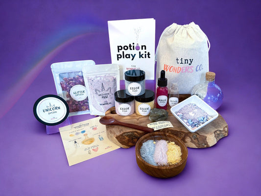 Potion play kit with unicorn theme placed with various items on a purple background